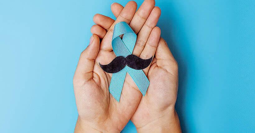 Prostata-MRT Schlüsselbild: zwei Hände umschließen behutsam die hellblaue Schleife, die als Symbol für Krebserkrankung und Früherkennung steht.